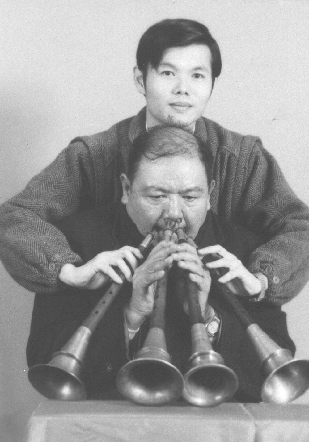 祖父陈庆松（前）展演同时吹奏4把唢呐的绝技，郑荣兴（后）替祖父扶著其中2把。