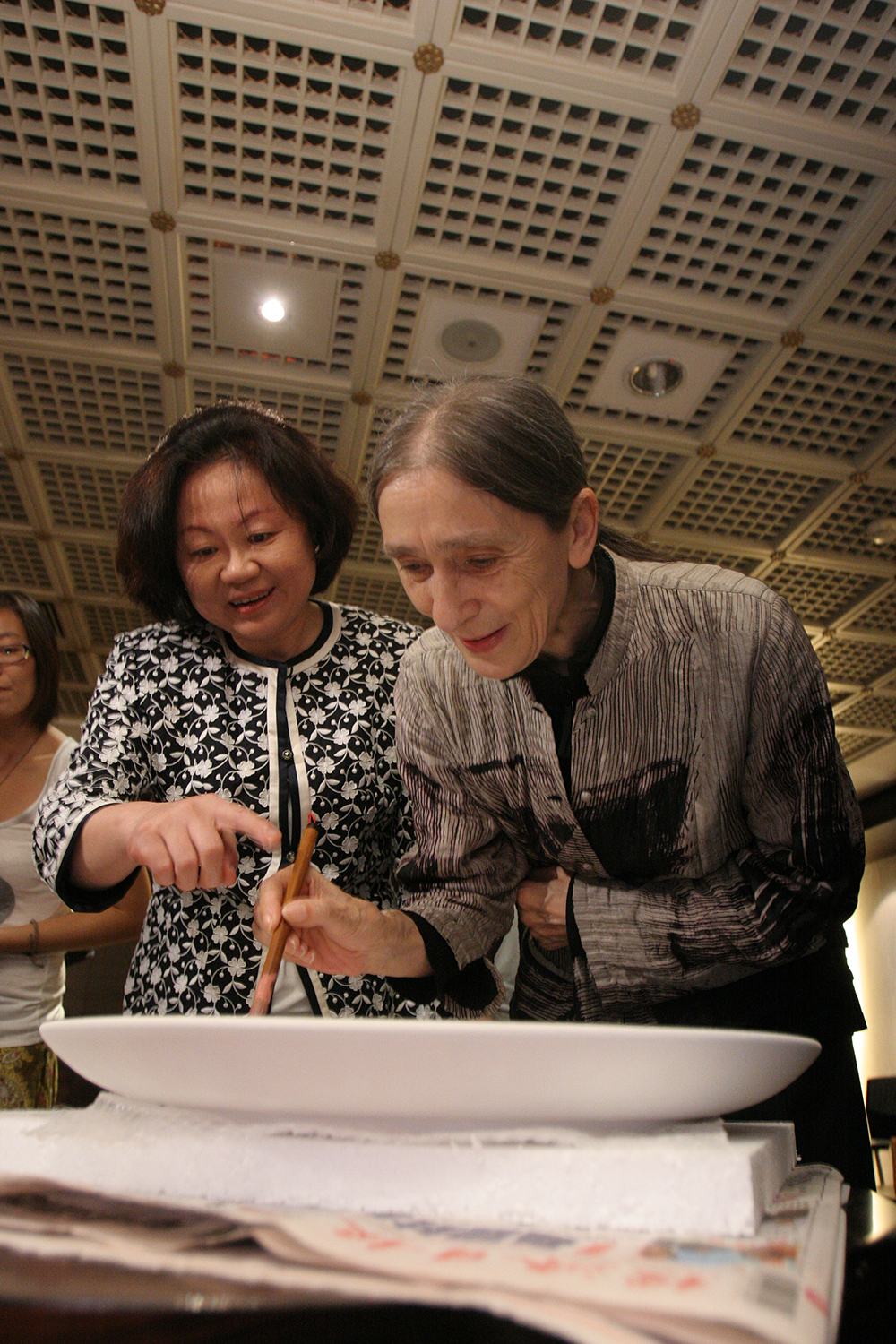 舞蹈大師碧娜．鮑許在陶盤上簽名，兩廳院董事長陳郁秀一旁陪同。
